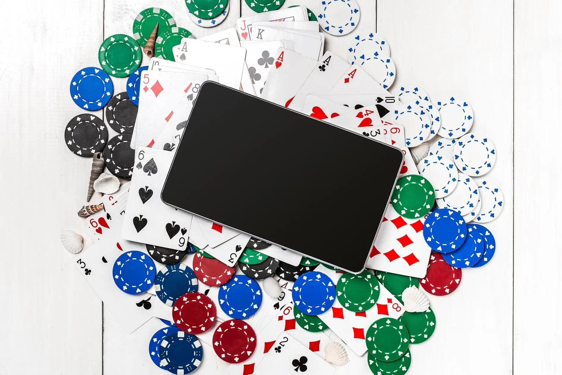 Smarttelefon omgitt av spillekort og pokerbrikker