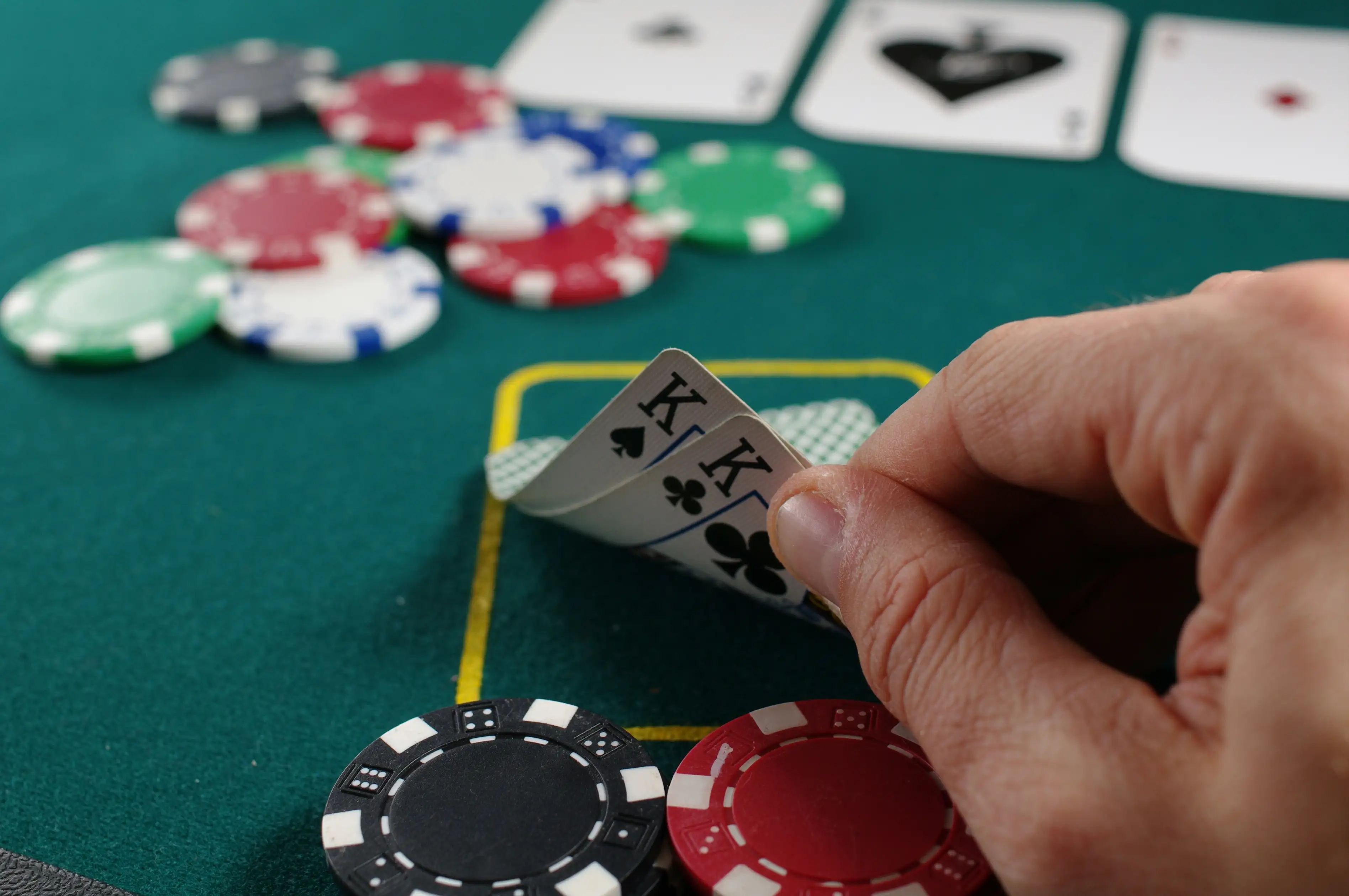 Hånd som holder spillekort over et pokerbord